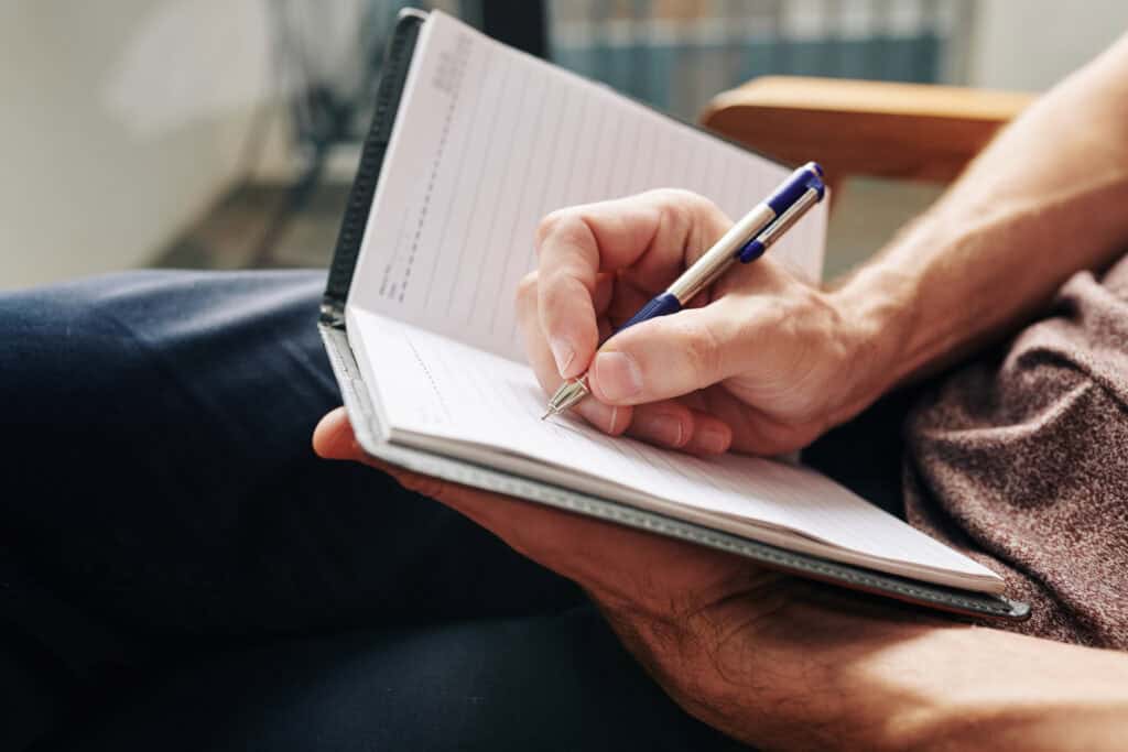 man writing down his tough day 